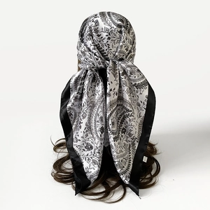 Detailweergave van een witte zijden sjaal met paisley-patroon in het haar