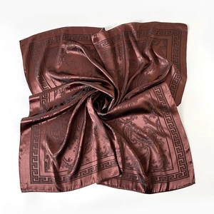 Détail d'un foulard en soie marron brillant avec motif paisley et bordure à la grecque
