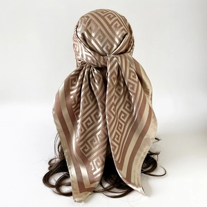 Detail of champagne gold silk-like scarf with brown geometric Greek key patterns