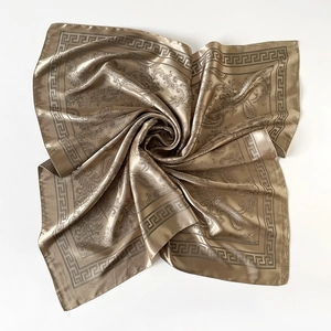 Détail macro du foulard en soie champagne avec paisley et bordure grecque dorée