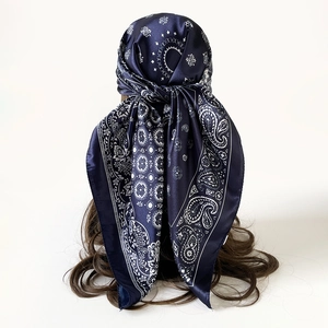 Detailweergave van een donkerblauwe zijden sjaal met wit paisley-patroon op golvend haar