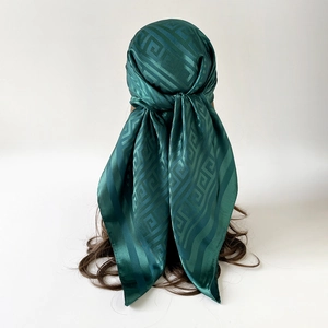 Detail of dark green silk scarf with geometric pattern worn as a stylish headwrap