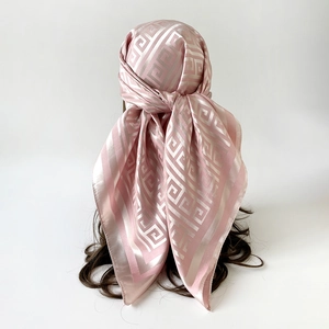 Detail of light pink silk-like scarf with champagne Greek Key pattern on a mannequin