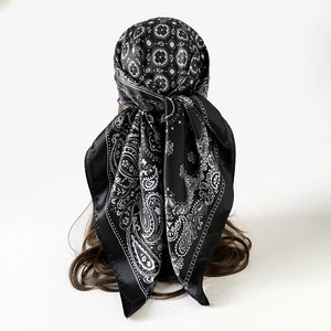 Detailweergave van de zwart-witte zijden sjaal met paisley-motief gedragen als hoofddoek