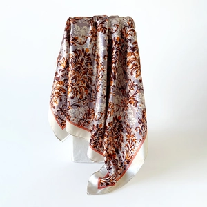 Detail of bohemian floral silk square scarf showing glossy texture and draped edges