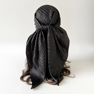Detail of black satin scarf tied on head featuring a classic Greek key geometric pattern