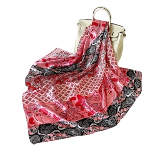Sciarpa di seta satinata rosa con motivo paisley e fiori su una borsa in pelle