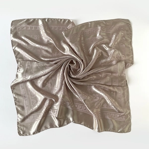 Détail d'un foulard en soie champagne doré avec bordure grecque et motifs de damas fleuri
