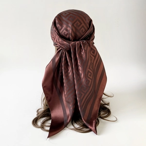 Detail of silk-satin square scarf with brown Greek Key geometric pattern texture