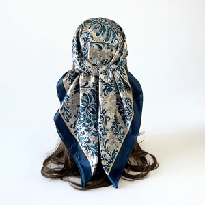 Detail view of floral satin headscarf tied in a triangular wrap style on a model head
