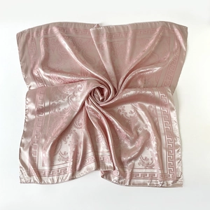 Détail d'un foulard en satin rose champagne avec motifs paisley et bordure grecque