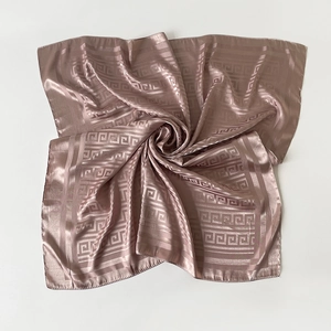 Detail of rose gold silk square scarf featuring elegant Greek key pattern borders