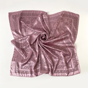 Détail d'un foulard en satin rose avec motifs paisley et bordure de style grec