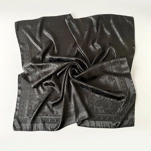 Détail d'un foulard carré en satin noir avec jacquard paisley et bordure à motif grec