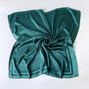 Close-up of elegant dark green silk square scarf with geometric pattern and satin sheen