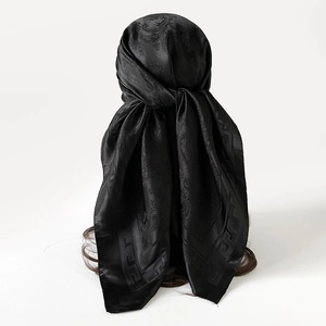 Détail d'un foulard noir en soie avec jacquard paisley et bordure Greca sur cheveux