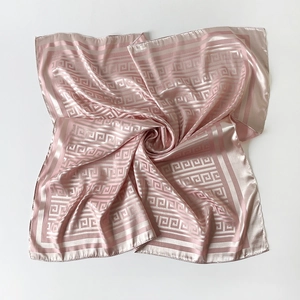 Macro shot of pink satin scarf with ivory Greek key patterns and a soft pearl finish