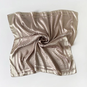 Detail of champagne silk scarf with Greek key pattern and elegant smooth texture
