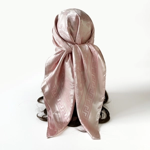 Détail du foulard en soie rose avec motifs paisley et bordure grecque en satin brillant