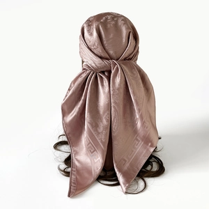 Détail d'un foulard en satin rose avec motif cachemire et bordure à la grecque