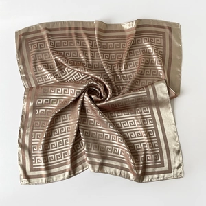 Detail of silk scarf showing champagne gold Greek meander pattern and smooth texture