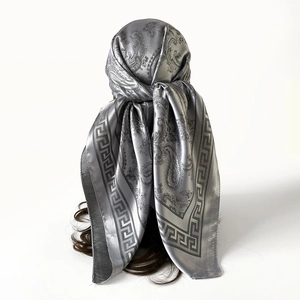 Détail d'un foulard en satin gris argenté avec motif cachemire et bordure grecque