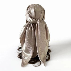 Détail d'un foulard en soie paisley doré noué comme un bandeau sur un mannequin