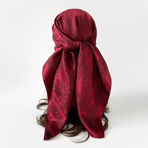 Détail macro du foulard en soie bordeaux avec motif paisley et bordure grecque chic