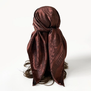 Détail macro du foulard en soie satinée marron foncé avec motif paisley élégant