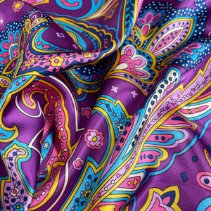 Detailed macro shot showing the glossy drape and purple Paisley pattern of the satin scarf