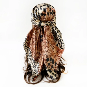 Detailaufnahme eines Satin-Quadrat-Schals mit Leopardenmuster, elegant im Haar gebunden