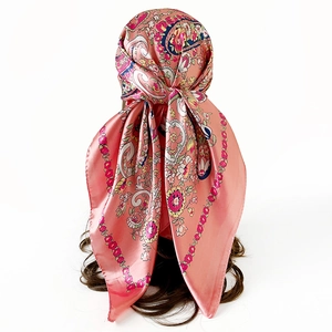 Detail view of pink paisley satin scarf tied in hair showing smooth silk texture and pattern