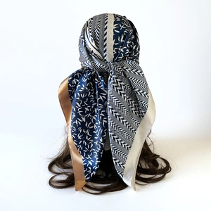 Detail of satin silk scarf tied on brunette hair with navy blue and gold floral patterns