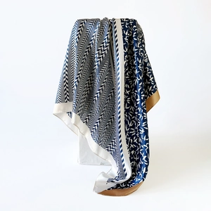 Macro detail of the smooth satin texture and geometric bird print on a navy silk scarf
