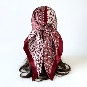 Detail of burgundy and cream satin scarf with bird print worn as a chic headscarf