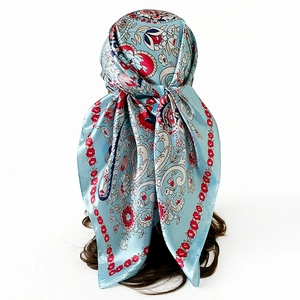 Detailed pattern of blue satin square scarf featuring red floral and paisley prints