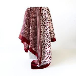 Close-up of smooth satin scarf with elegant burgundy bird and herringbone print texture
