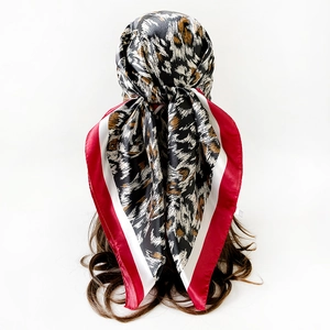 Dettaglio di foulard in raso leopardato come turbante con bordo rosso e bianco a contrasto