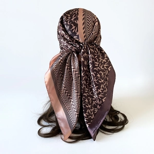 Detail view of 90cm satin square scarf with geometric bird print worn on head