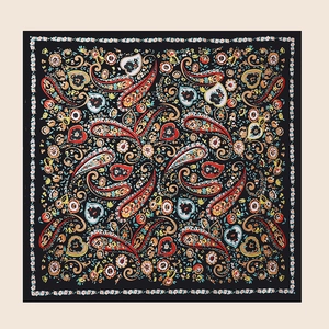 Close-up of square satin scarf showing detailed paisley patterns and floral borders on black
