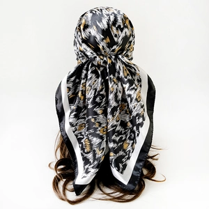 Dettaglio di un foulard quadrato in raso maculato legato sui capelli lunghi