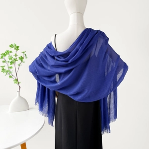 Detalle de chal de lino azul oscuro con bordes deshilachados en un maniquí blanco