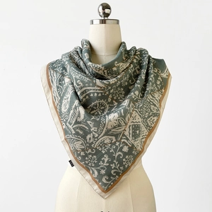 Détail d'un foulard en soie vert sauge avec motif paisley blanc sur un mannequin