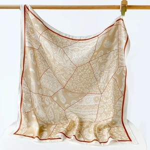 Détail du motif paisley vintage sur un foulard en soie beige avec imprimé floral