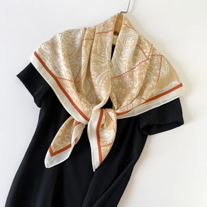 Détail d'un foulard en soie vintage à motif paisley sur un cintre en bois, fond blanc