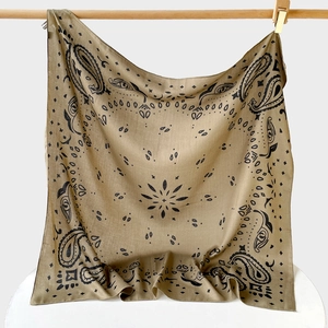 Detail of khaki paisley silk scarf showing intricate black floral patterns on wood bar