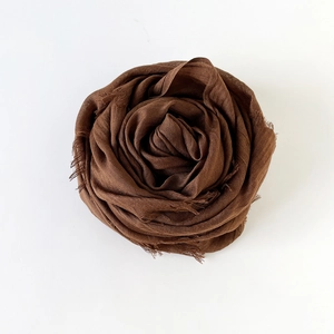 Detailed texture of dark brown cotton linen scarf with soft fringe and elegant drape