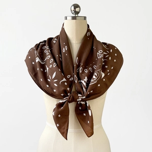 Detail of a brown paisley silk scarf with rose patterns displayed on a mannequin