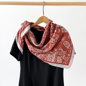 Détail d'un foulard en soie rouge vintage avec motifs floraux cachemire élégants blancs