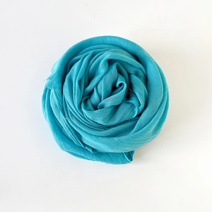 Close-up of turquoise cotton linen scarf tied in a rose knot with delicate fringe edge